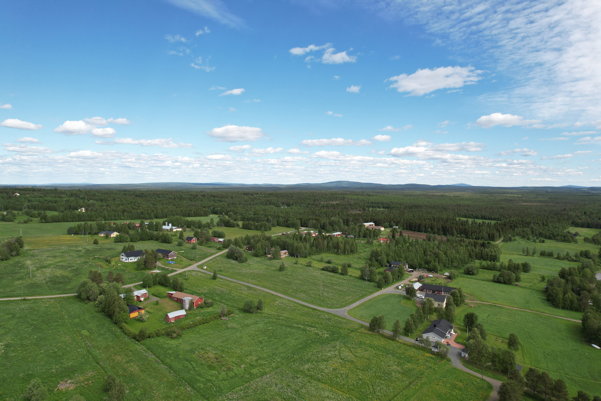 Määttälänvaaran kylämaisema. Etualalla punainen talo, navettarakennus ja aittarakennus. Oikealla kaksi erillista valkoista taloa. Taustalla metsää ja muutama asuonrakennus.