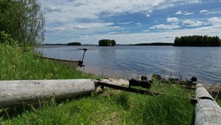 Kyläniemen veneenlaskupaikka Suininkijärvellä. Rannassa vene järven rannassa. Taustalla järvimaisemassa pieniä saaria.